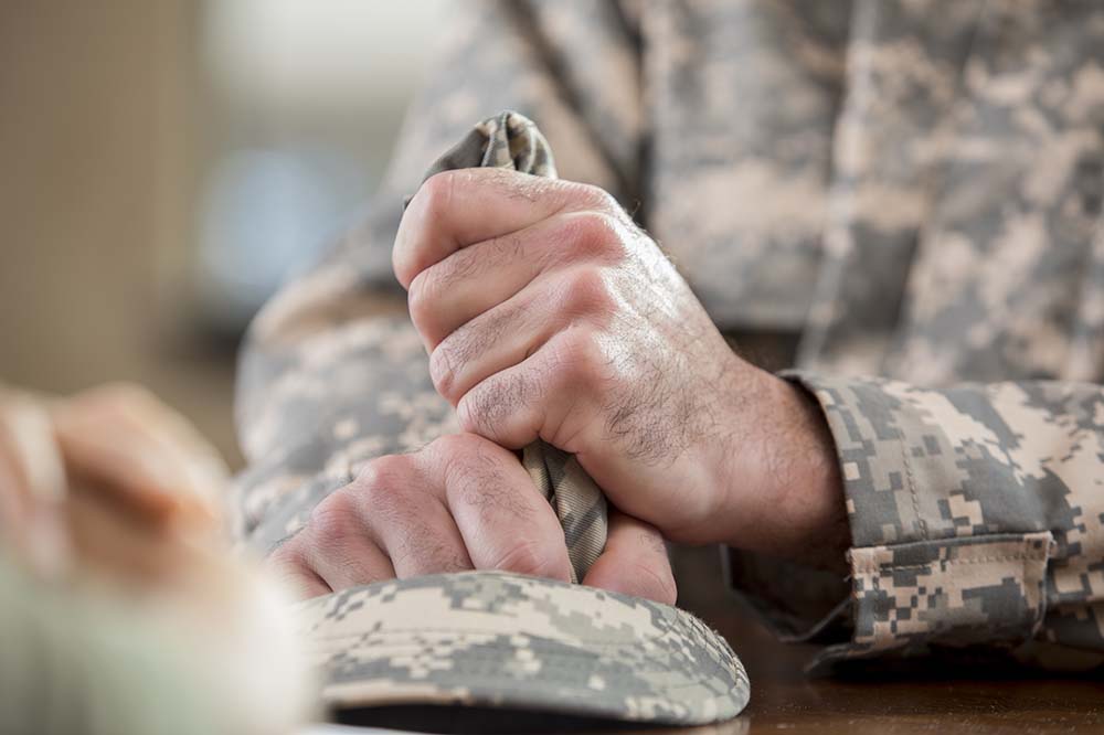 Closeup of white man's hands. He's wearing camouflage.