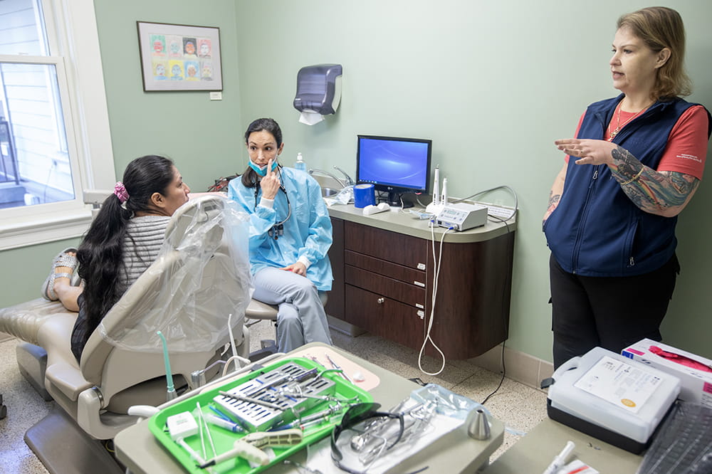 Endodontic chief resident Dr. Ann Nicholas talks with a patient via a Spanish-speaking interpreter to explain her care and follow up. 