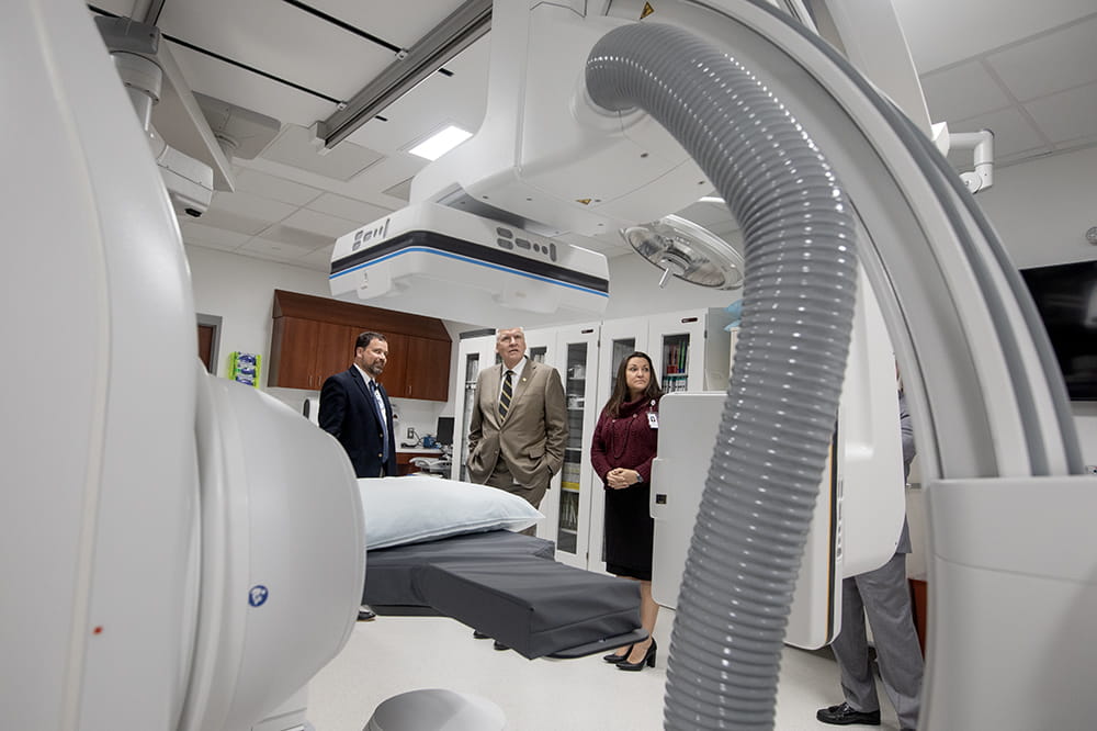 Three people look at a giant fancy piece of medical equipment