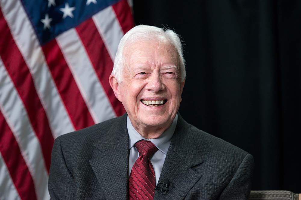 Headshot of former President Jimmy Carter. He's wearing a suit and tie and smiling.