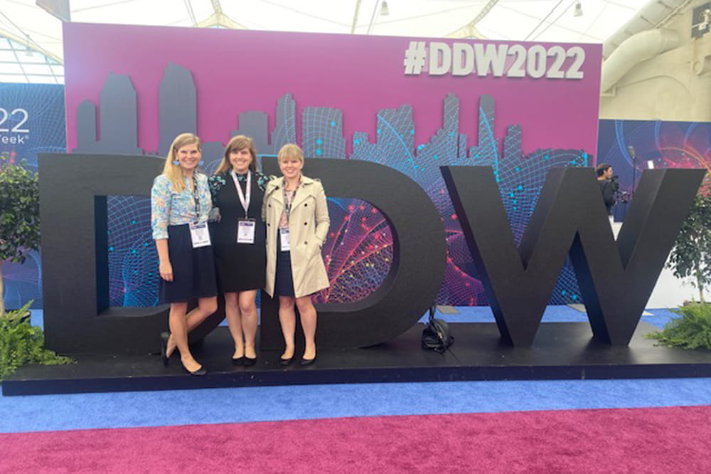 three women pose in front of head-height letters DDW