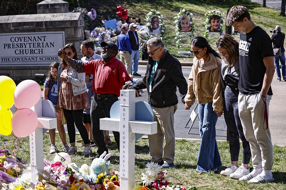 A group of people gathered in front of two white crosses. You can see a sign that says Covenant Presbyterian Church in the background.