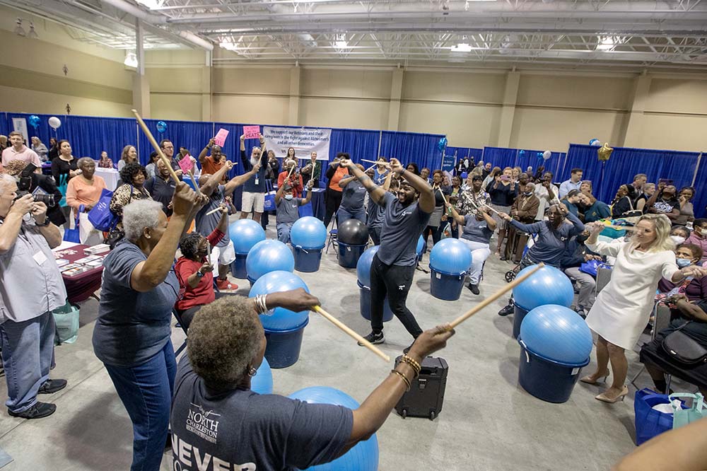 A crowd of people holding thin sticks over blue balls.