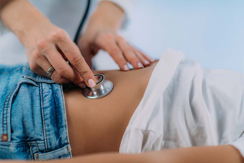Hands put a stethoscope on a child's bare stomach.