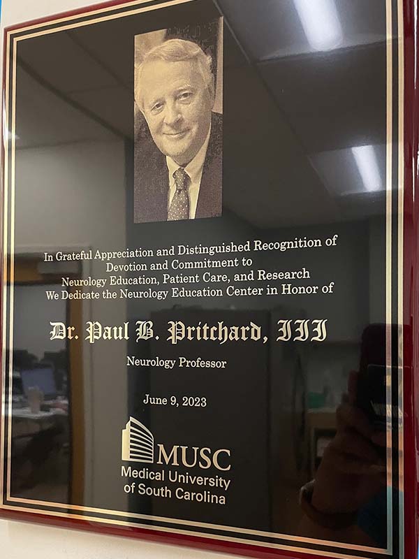 Plaque shows photo of a man and says in grateful appreciation and distinguished recognition of devotion and commitment to neurology education, patient care, and research we dedicate the neurology center in honor of Dr. Paul B. Pritchard III, June 9, 2023