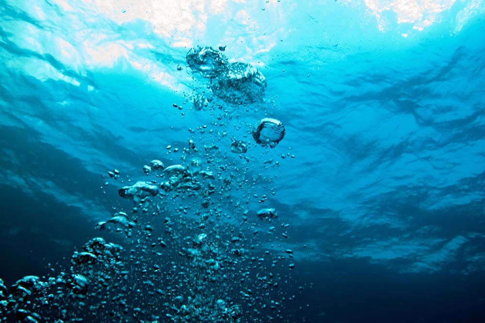 Bubbles rise to the surface of blue water.
