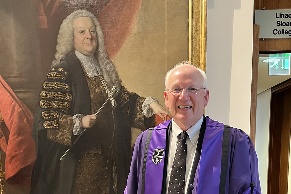 Dr. Ray DuBois poses in front of an oil painting at the Royal College of Medicine