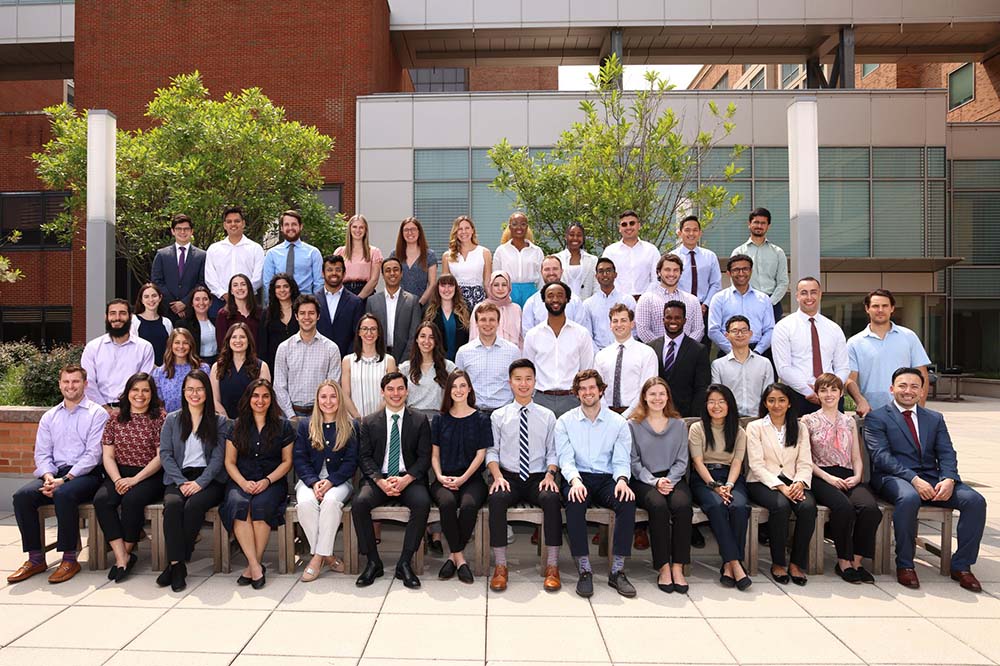 Large group of young people wearing dress clothes pose for a picture.