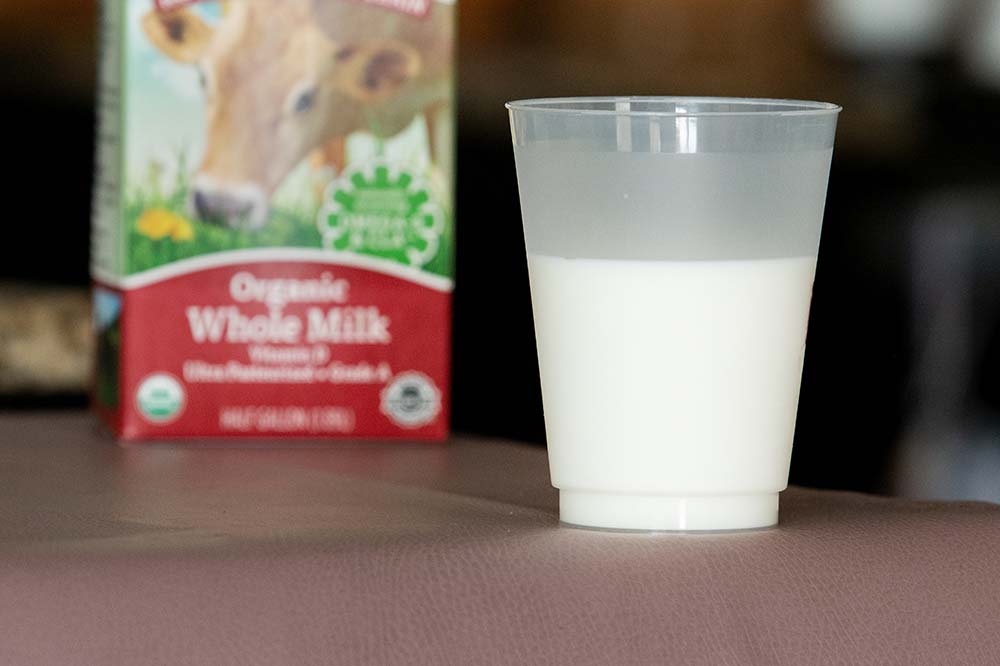 cup of milk beside carton that says organic whole milk.
