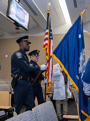 Two officers in blue uniforms carry the U.S. and South Carolina flags.