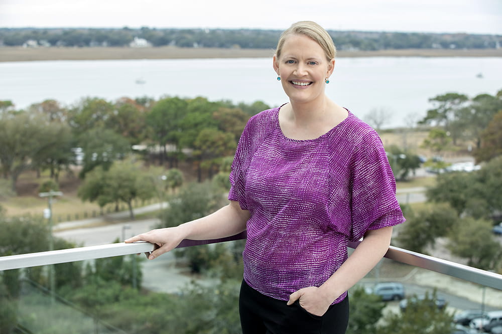 Dr. Caitlin Allen standing on a balcony, with Ashley River in background.
