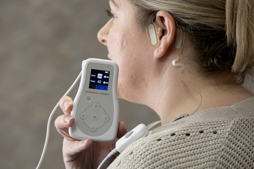 Team member demonstrating transcutaneous auricular neurostimulation, a wearable technology that alleviates pain by directly stimulating nerves in the ear with electricity.