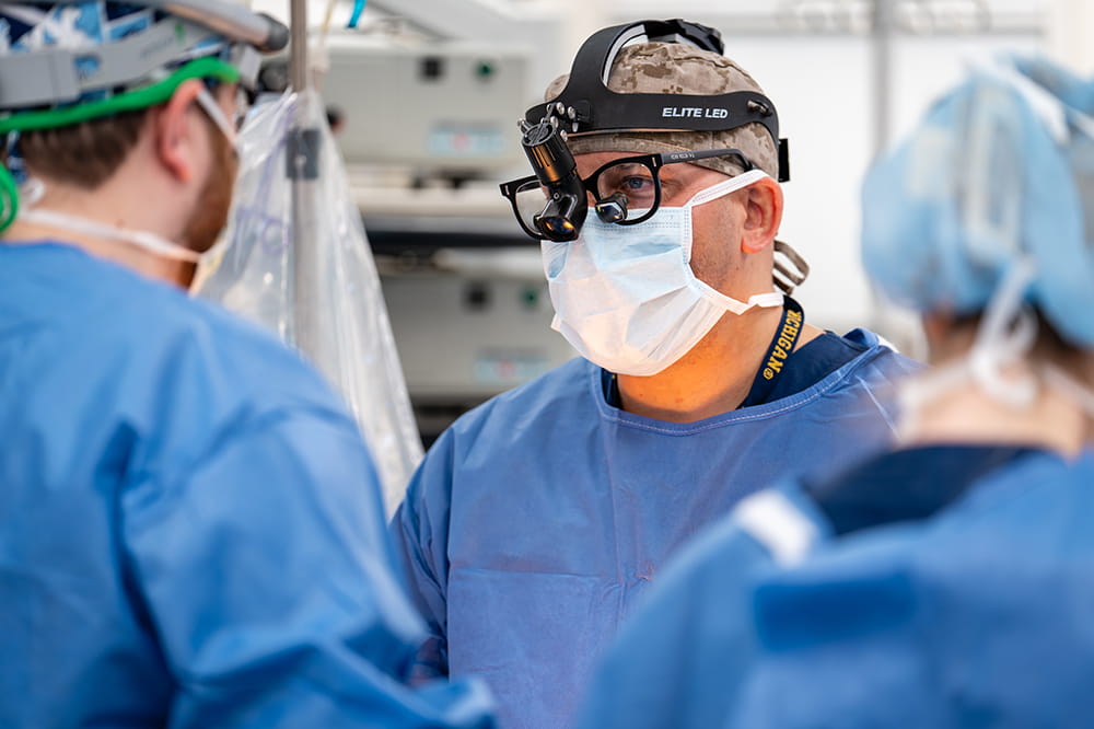 a cancer surgeon in the operating room looks up to talk to a team member