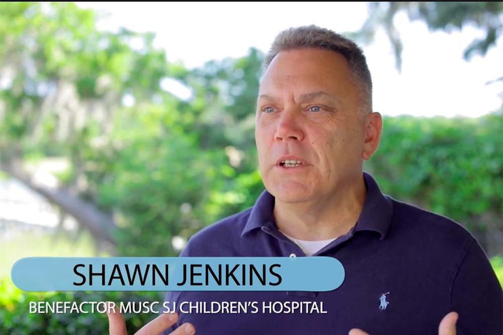 Man wearing a blue polo gestures. The words Shawn Jenkins, benefactor MUSC SJ Children's Hospital appear at the bottom of the screen.