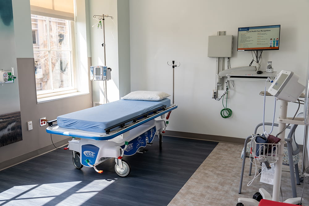 an empty hospital bed sits in the sunshine streaming through a window