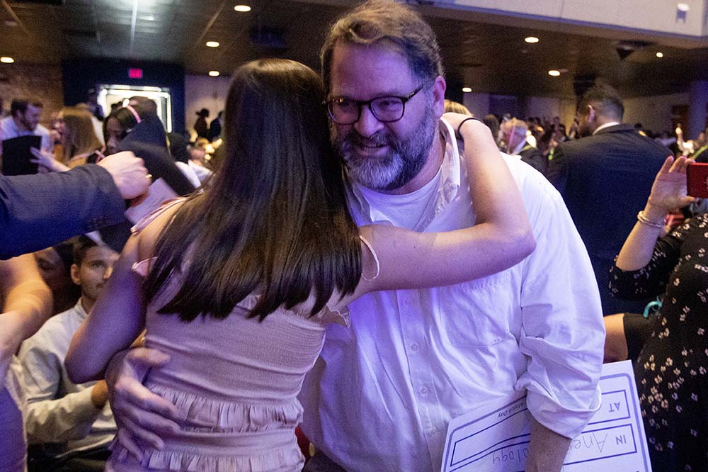 Young woman hugs man with glasses and beard.