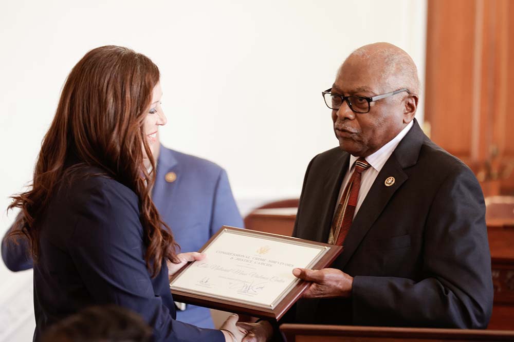 Woman receives plaque from a man. Both are wearing dress clothes.