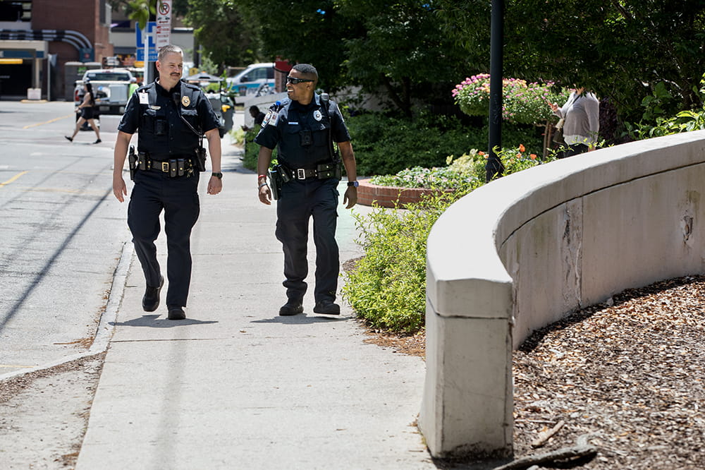 Two uniformed officers walk on a sidewalk.