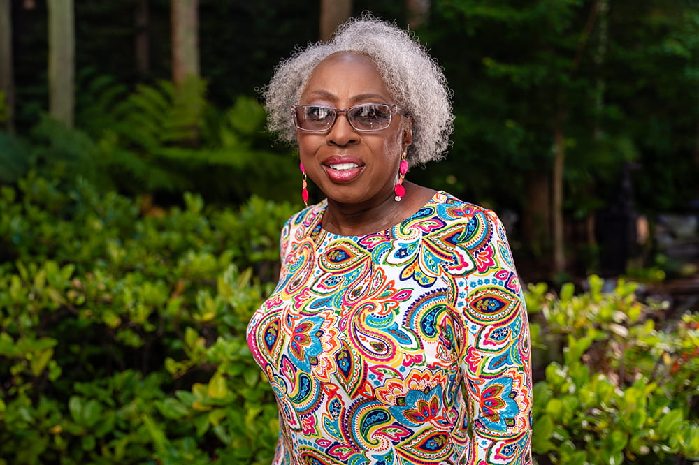 triple negative breast cancer survivor Sarah Harry poses in a colorful dress in a swirling pattern in the garden