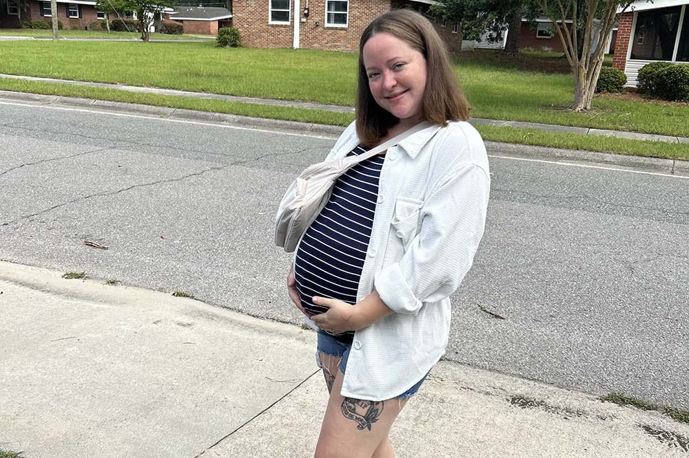 Smiling woman holds her pregnant belly.