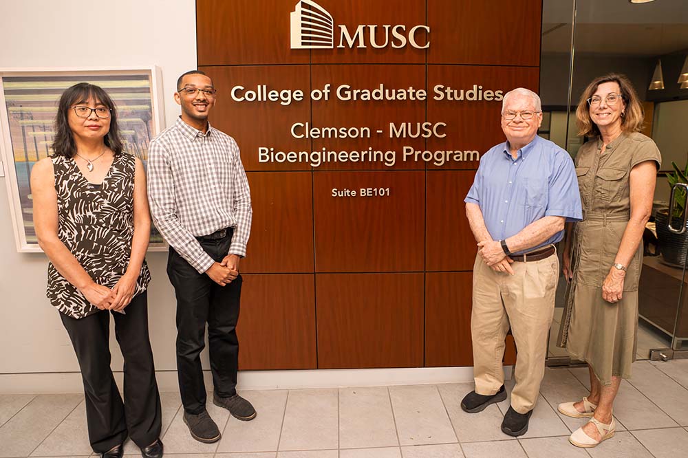 Four people stand by a sign that says MUSC College of Graduate Studies.