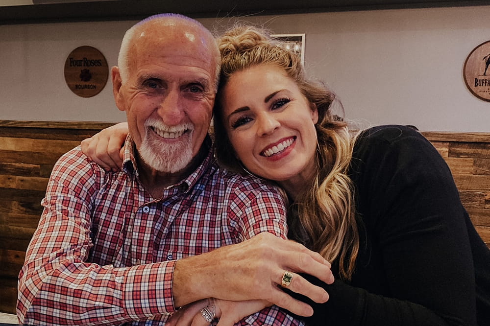 a young woman hugs her father while they sit next to each other in a restaurant