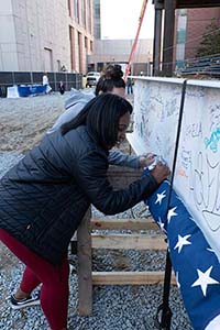 two young women sign a construction beam