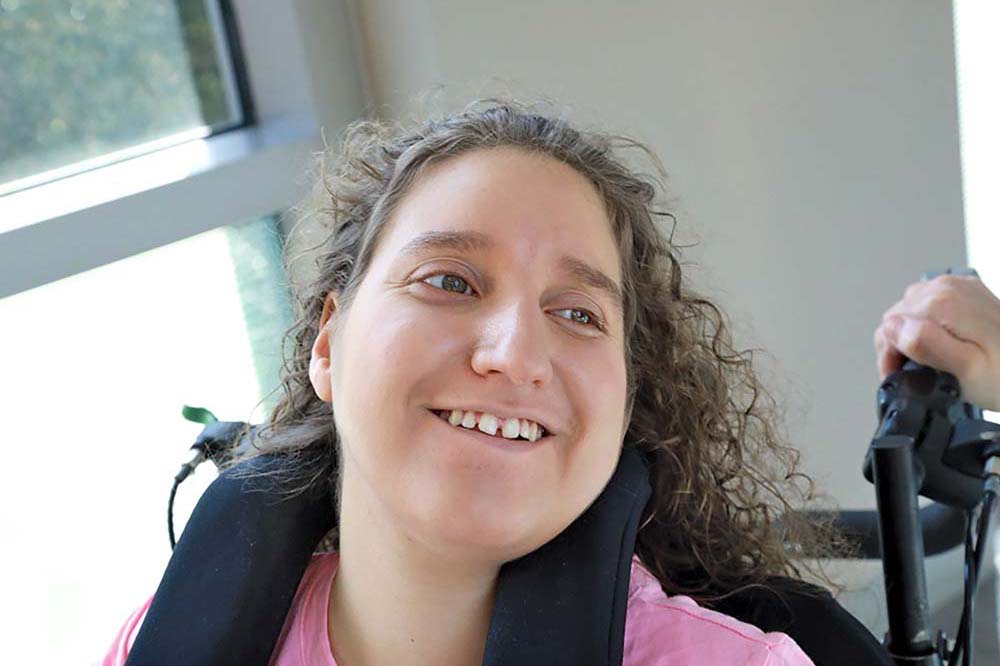 Young woman with curly brown hair smiles.