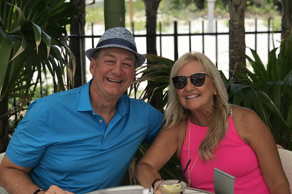  a man and woman sit in an outdoor cafe and smile at the camera