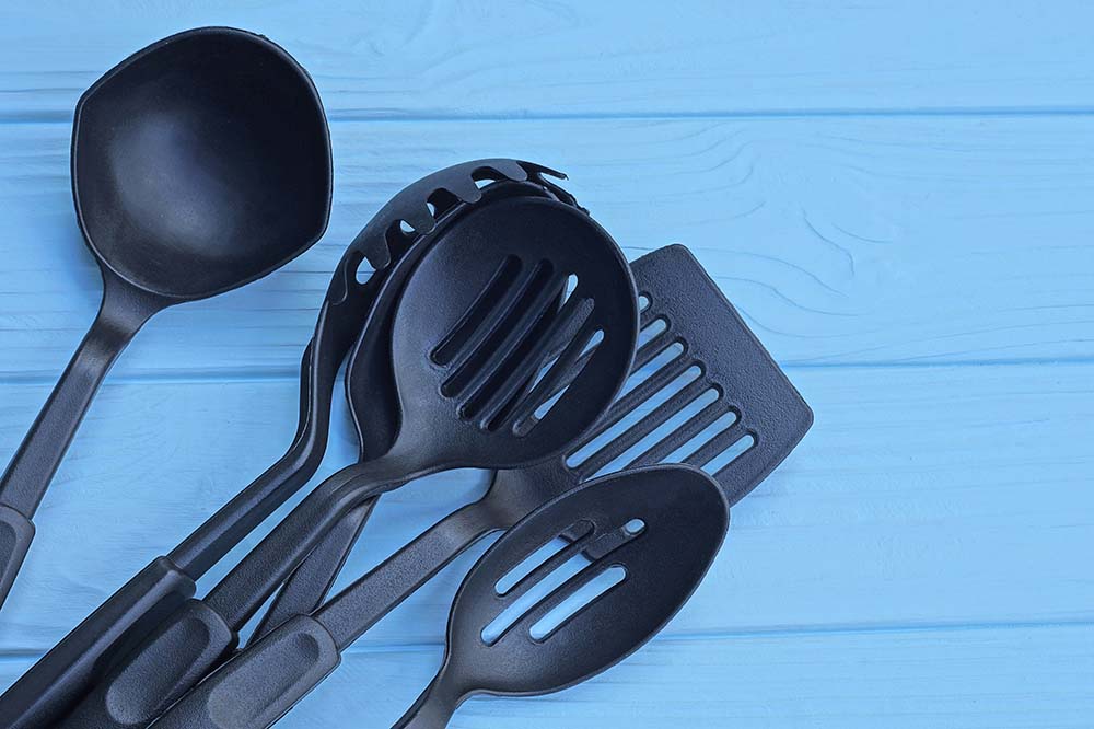 Five black kitchen utensils on a blue background.