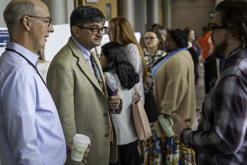 People stand in a hallway discussing research posters.