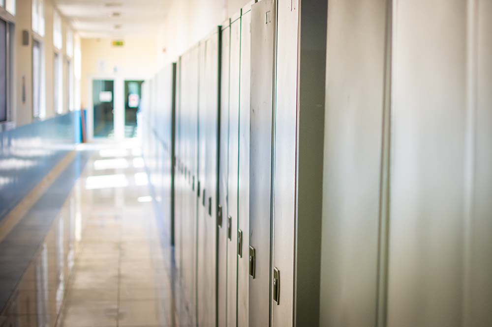 Empty corridor with light at the end. Lockers line the right side.