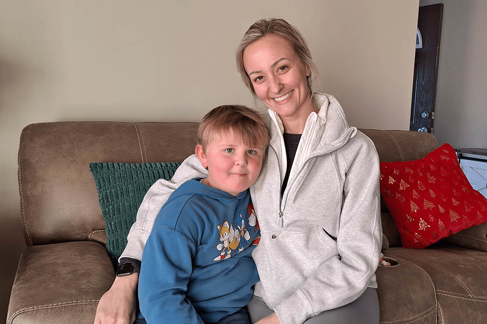 a young boy poses with his mom on the sofa in their living room