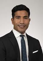 Headshot of a smiling man wearing a coat and tie.