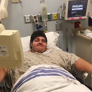 Young man lies in hospital bed.