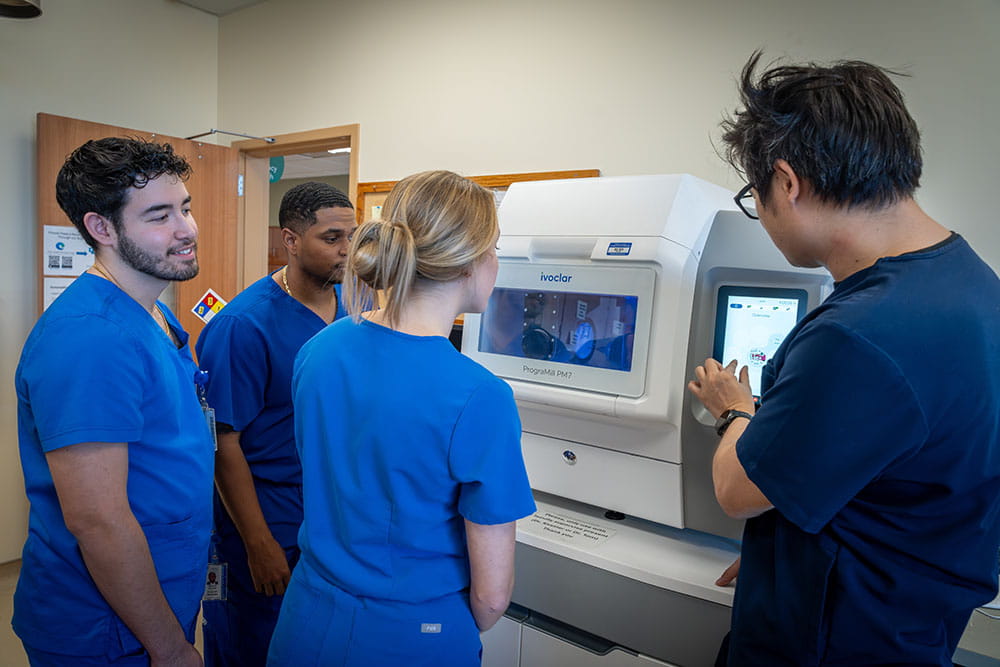 Students looking at scanning machine in dental innovation lab.