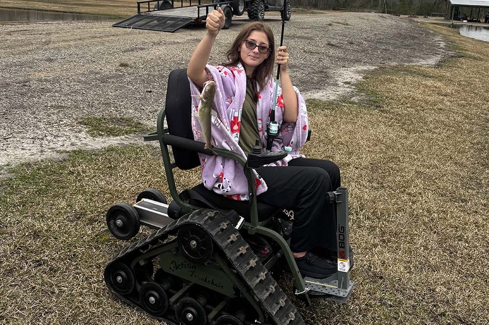 Girl wearing sunglasses in a wheelchair that looks like a small tractor.