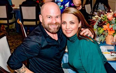 a couple poses together at a table at a fancy dinner
