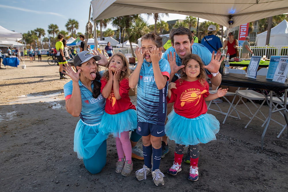 a mom and dad and three little kids make goofy faces at the camera
