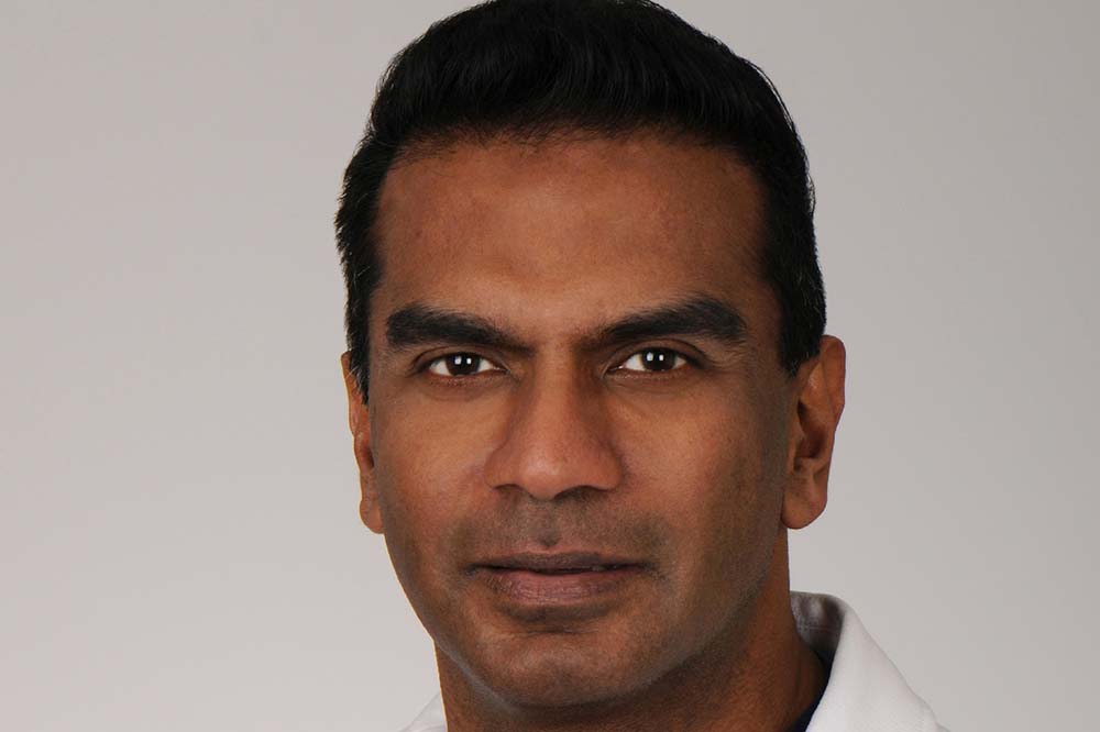 Headshot of a man with dark hair. You can see part of the collar of his white coat.