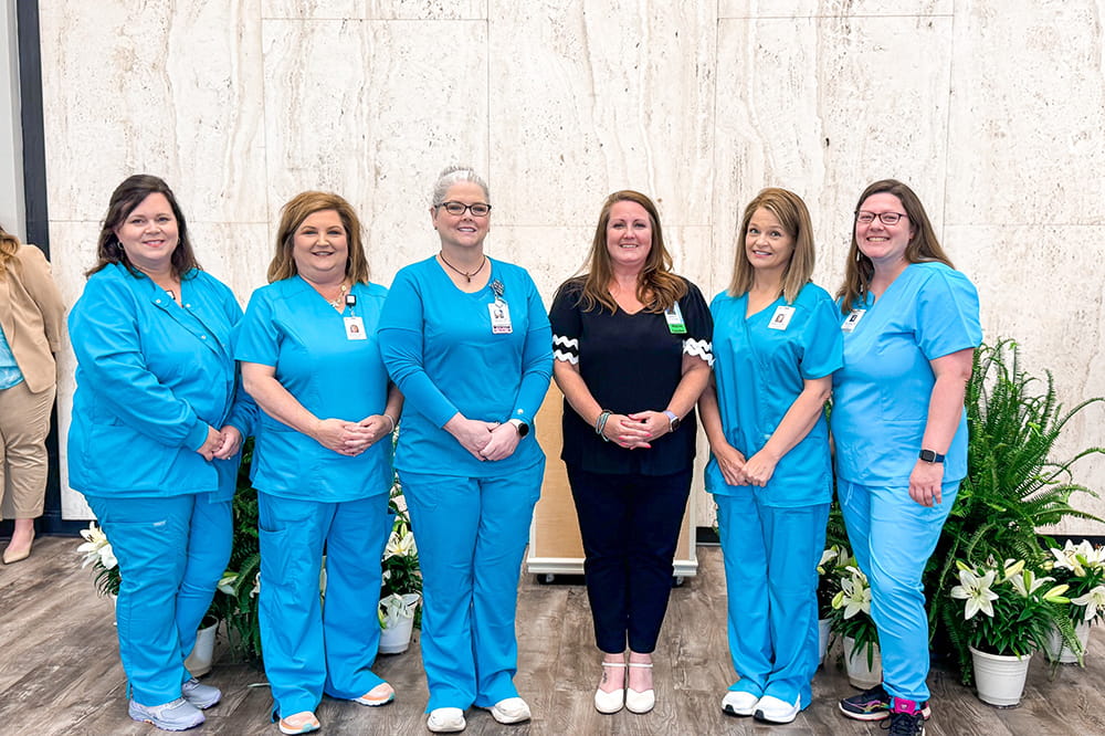 Six nurses standing together posing for a picture in scrubs. 
