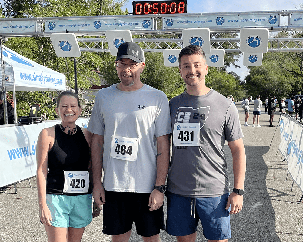 Three people standing at the finish line of a race