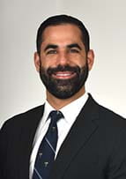 Headshot of a bearded man wearing a dark suit and tie.