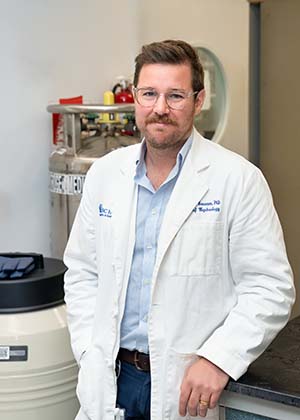 Man with a beard and glasses wearing a white lab coat.
