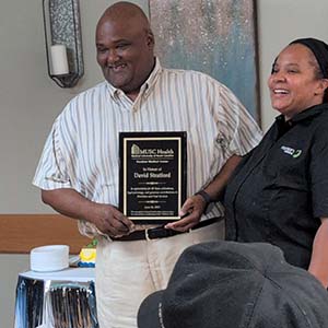 Smiling man holds a plaque that says MUSC Health Kershaw Medical Center in honor of David Stratford. In appreciation for your 50 years of kindness, loyal patronage and generous contributions to Nutrition and Food Services. June 24, 2025