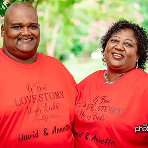 A smiling man and woman wearing red t-shirts that say a true love story never ends-David and Annette.