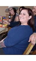 Smiling woman with a blue shirt sits at table.