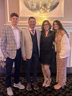 Four people in dress clothing smile as they stand together.