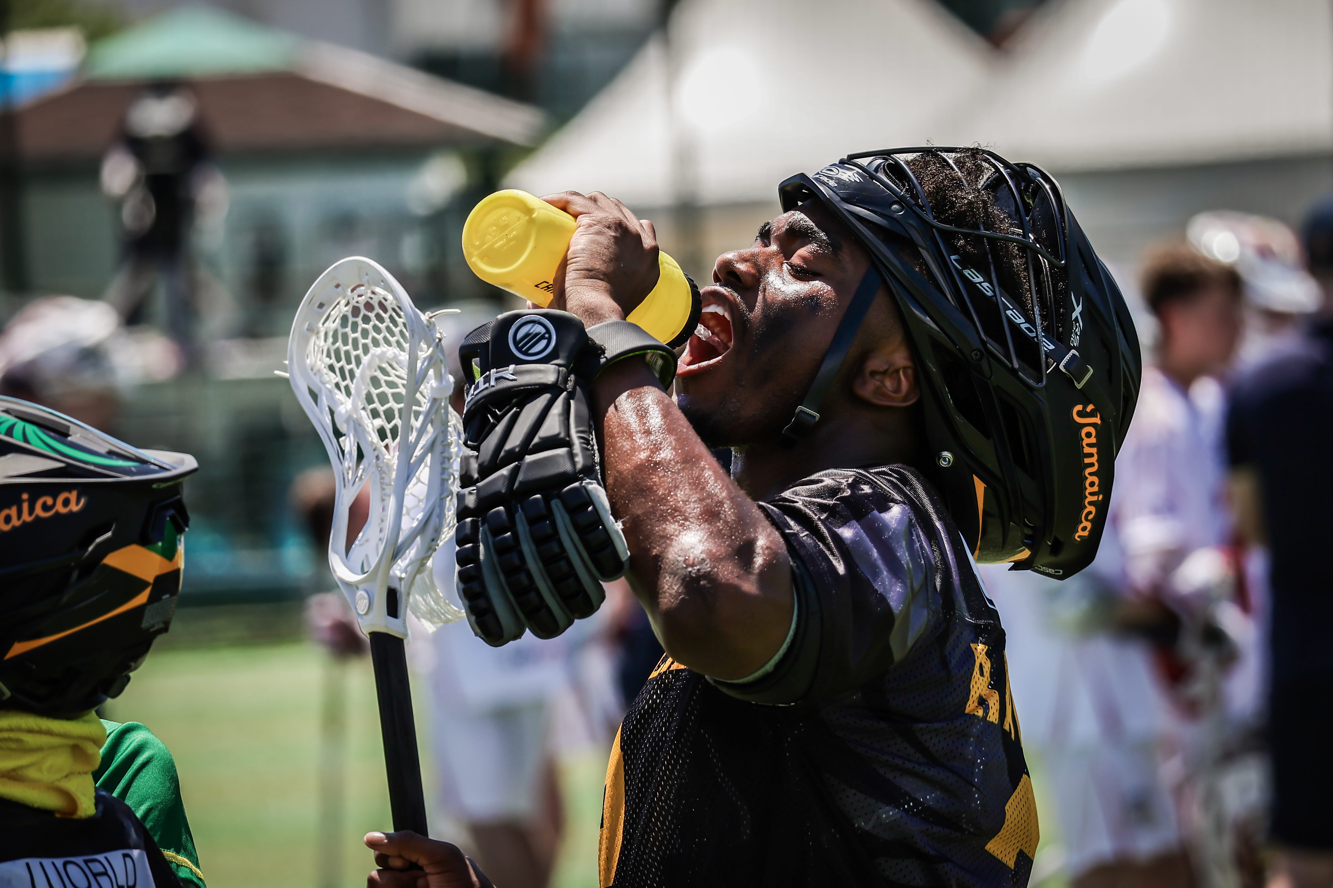 Man in a blue and gold uniform holds a yellow water bottle as he drinks from it.