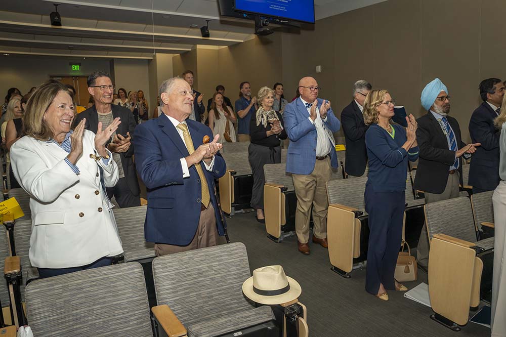 People stand and applaud in an auditorium